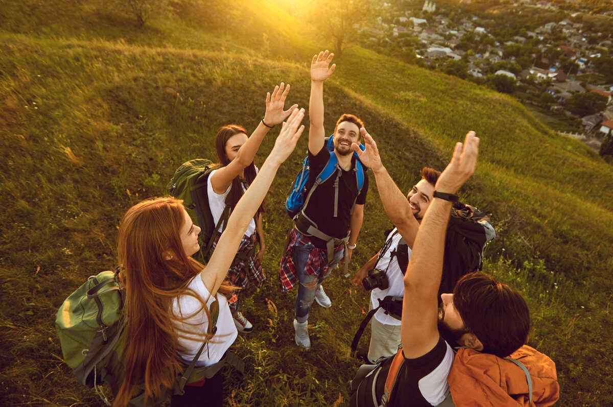 echipă de colegi în activitate de teambuilding montan, entuziasm și reușită la apus